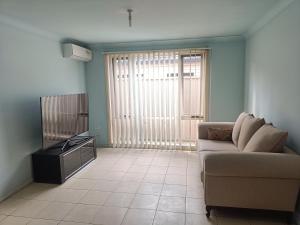 a living room with a couch and a television at Budget Queen Room - 493 in Wentworthville