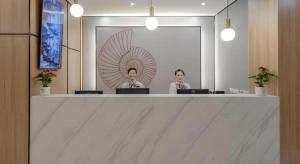 two women sitting at a counter in a room with laptops at Shell Hotel Shnaghai Beiqiao Metro Station in Shanghai