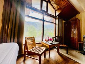マナリにあるHotel Fast Way Manali #Near zingbus #Near Pizzahut #By silverlandのベッドとテーブルと窓のある寝室