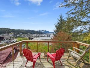 two red chairs on a deck with a view of a harbor at Family Getaway in Juneau, Alaska Unforgettable Ocean and Mountain Views in Mendenhaven