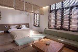 a bedroom with a bed and a couch and windows at Xiamen Bashi Living Room B&B 厦门八适客厅民宿 in Xiamen