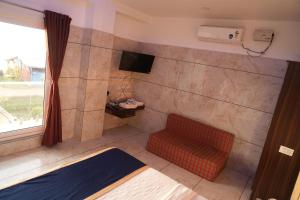 a room with a bed and a television and a chair at Blue Pearl Beach Guest House in Māvalli