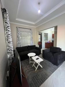 een woonkamer met een zwarte bank en een tafel bij The Black mamba in Arusha