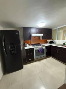 a kitchen with a black refrigerator and a stove at Casa de dos pisos,Ciudad Tolteca in Tula de Allende