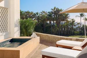 a patio with a pool and chairs and an umbrella at One&Only Palmilla in San José del Cabo