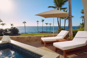 a swimming pool with two chairs and an umbrella at One&Only Palmilla in San José del Cabo