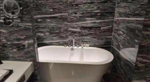 a bathroom with a white sink and a stone wall at Ramada by Wyndham Wuhan Dongxihu in Wuhan +26 photos