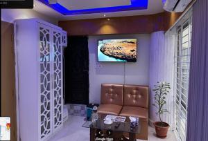 Hotel The Manha LTD Purana Paltan في داكا: غرفة انتظار مع كرسي وتلفزيون على الحائط