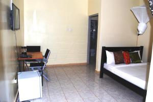 1 dormitorio con cama, mesa y escritorio en Dich Comfort Hotel - Main Branch en Gulu