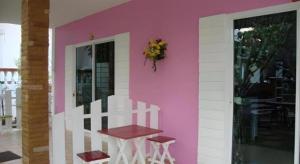 a pink wall with a table on the side of a house at Baan Gon Chompu in Suan Phung