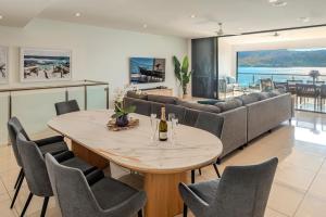 a dining room with a table and chairs and a couch at Edge 2 - Oceanfront Luxurious and Spacious 4 Bedroom Split Level Apartment with buggy and valet service in Hamilton Island