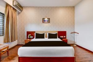 une chambre avec un grand lit dans une pièce dans l'établissement Super Townhouse Oak Sri Mahadeshwara Convention Centre Formerly Shri Aprameya Resort, à Hārohalli