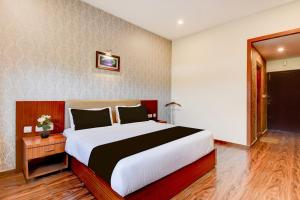 une chambre avec un grand lit dans une pièce dans l'établissement Super Townhouse Oak Sri Mahadeshwara Convention Centre Formerly Shri Aprameya Resort, à Hārohalli