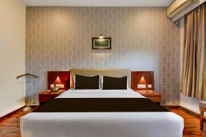 une chambre avec un grand lit et deux lampes dans l'établissement Super Townhouse Oak Sri Mahadeshwara Convention Centre Formerly Shri Aprameya Resort, à Hārohalli