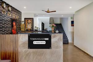 Super Townhouse Oak Sri Mahadeshwara Convention Centre Formerly Shri Aprameya Resort في Hārohalli: ردهة منزل مع لافتة على المنضدة