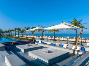 een zwembad met stoelen en parasols naast het strand bij Ocean Spring Metropark Hotel Zhuhai in Dahu