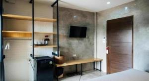 a room with a bed and a desk and a television at Journey Hostel Surat in Ban Tha Kup