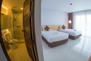 a hotel room with two beds and a bathroom at Chaisaeng Villa in Sing Buri