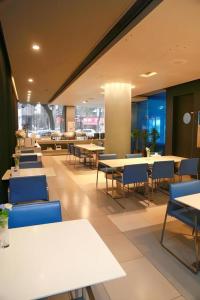 een restaurant met tafels en blauwe stoelen en tafels bij Jinjiang Inn Yueyang Railway Station in Yueyang