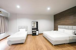 twee bedden in een kamer met witte muren en houten vloeren bij CHANTHABURI CENTER in Chanthaburi +98 foto's