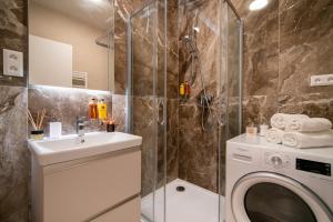 a bathroom with a washing machine and a sink at apartino - free parking v okolí - in the neighbourhood, city view balcony, nespresso, netflix in Komárov