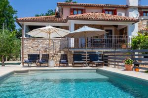 a house with a swimming pool with chairs and umbrellas at House Matija in Svetvinčenat