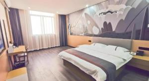 a bedroom with a large bed with a painting on the wall at Thank Inn Plus Hotel Jiangyin University in Wuxi