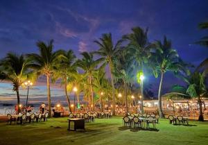 een groep tafels en stoelen op het strand 's nachts bij Lago de Oro in Balibago