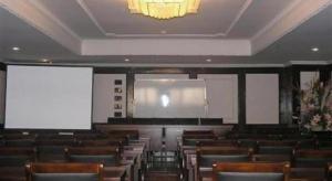 a lecture hall with wooden chairs and a projection screen at GreenTree Inn Zhangjiagang Yangshe Old Street Stadium in Zhangjiagang