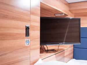 a television in a room with a wooden wall at HOTEL LiVEMAX Toyooka in Toyooka