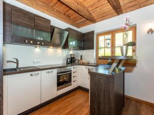 a kitchen with white cabinets and a wooden ceiling at Apartment Wiesbachhorn Zell am See-Kaprun in Kitzsteinhorn