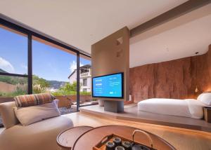 a bedroom with a bed and a tv in a room at Zhangjiajie Shisuji Hotel (Zhangjiajie National Forest Park Sign Gate Branch) in Zhangjiajie