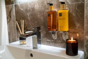 a bathroom sink with two bottles of soap and a candle at apartino - FREE parking - Novostavba - Omezený přístup a stavební ruch - New Building - Limited Access and Construction noise in Komárov +17 photos