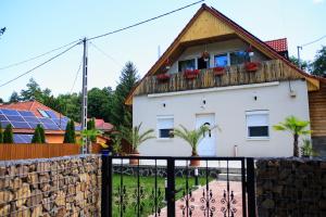a white house with a balcony and a fence at Country Vendégház in Szilvásvárad