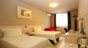 a hotel room with two beds and a red chair at Jinjiang Inn Zhoushan Putuo Shenjiamen in Xi'ao