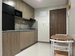 a kitchen with wooden cabinets and a table and a microwave at Aspen Suites Condo in Davao City