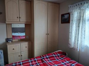 um quarto com uma cama e armários e uma janela em Charming 6 Berth Caravan With Decking By The Beach In Suffolk Ref 40107Nd em Gunton