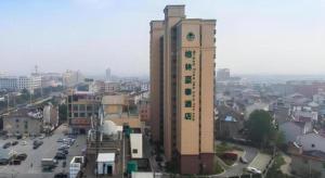 een hoog gebouw met een klokkentoren in een stad bij GreenTree Inn Maanshan Hanshan District Jiuwu Square Hotel in Jiulian