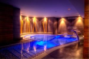 a swimming pool with blue lights in a building at Hotel Spa El Muelle de Suances in Suances
