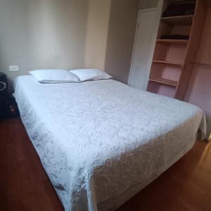 a bedroom with a bed with a white comforter at Base Rebelde 77 in Quilpué