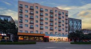 a large pink building in front of a building at Zhangye Pinmu Hotel(Yuncheng Zhongyin Avenue Store) in Yuncheng