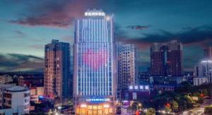 un edificio alto con luces encendidas en una ciudad en Kyriad Marvelous Hotel Xiangyin Bus Station, en Xiangyin