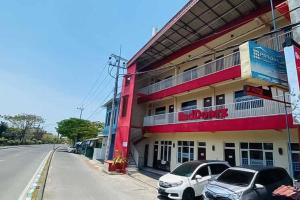 a building with two cars parked in front of it at RedDoorz Syariah near T1 Juanda Airport 2 in Surabaya