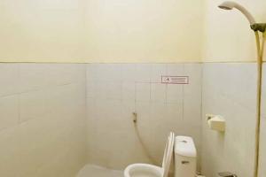 a white bathroom with a toilet and a shower at RedDoorz Syariah near T1 Juanda Airport 2 in Surabaya +6 photos