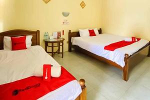 a room with two beds with red and white sheets at RedDoorz Syariah near T1 Juanda Airport 2 in Surabaya