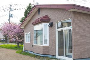 una casa marrone con finestre bianche e un albero di Mother River Stays -Stream Inn Shibetsu- Vacation Home, Gateway to Shiretoko & Nemuro Strait a Shibetsu