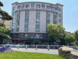 a large building with a fence in front of it at GreenTree Inn Jiaxing Tongxiang Tudian Express Hotel in T'u-tien-shih