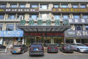 a building with cars parked in a parking lot at GreenTree Inn Jiangsu Zhangjiagang Jingang Town Darunfa Express Hotel in Xiwujieqiao