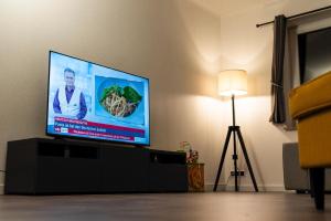 ein Flachbildfernseher in einem Wohnzimmer mit einer Lampe in der Unterkunft Strandnahe Ferienwohnung Nordsee Oase Whg. 1 in Cuxhaven