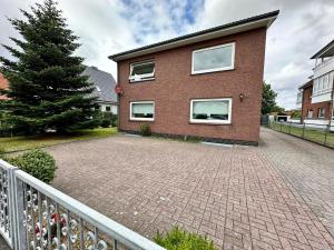 ein Backsteinhaus mit einem Zaun und einer Backsteinauffahrt in der Unterkunft Strandnahe Ferienwohnung Nordsee Oase Whg. 1 in Cuxhaven